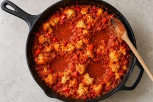 Blumenkohl und Paprikawürfel in Tomatensauce vor dem Einsetzen der Eier